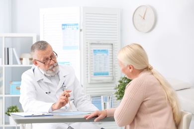 Coughing mature woman visiting doctor at clinic