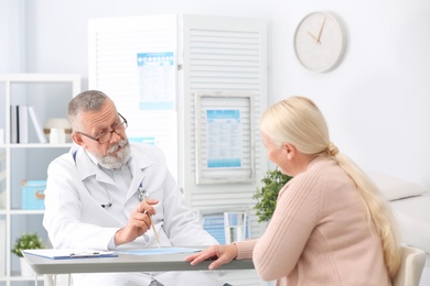 Photo of Coughing mature woman visiting doctor at clinic