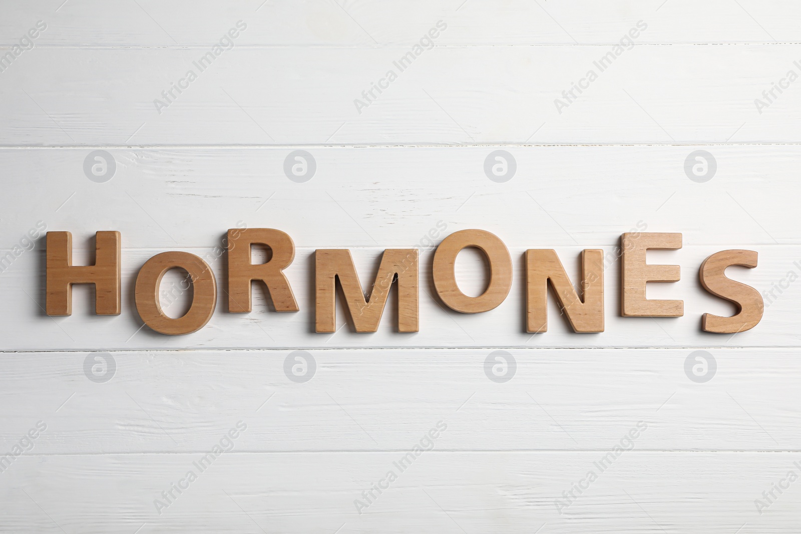 Photo of Word HORMONES made with wooden letters on table, flat lay