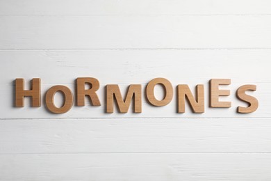 Word HORMONES made with wooden letters on table, flat lay