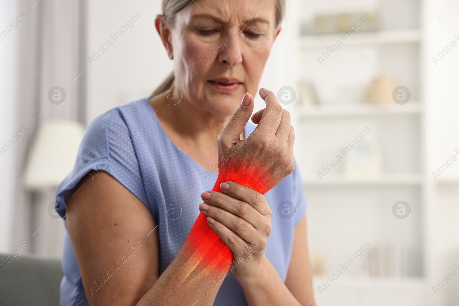 Image of Arthritis symptoms. Woman suffering from pain in her wrist indoors