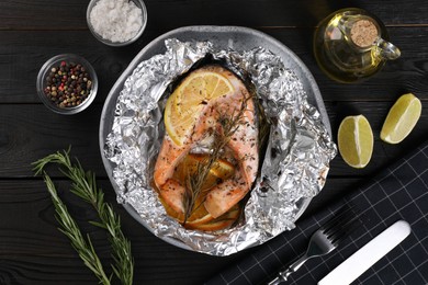 Tasty salmon baked in foil with lemon, spices and rosemary served on dark wooden table, flat lay