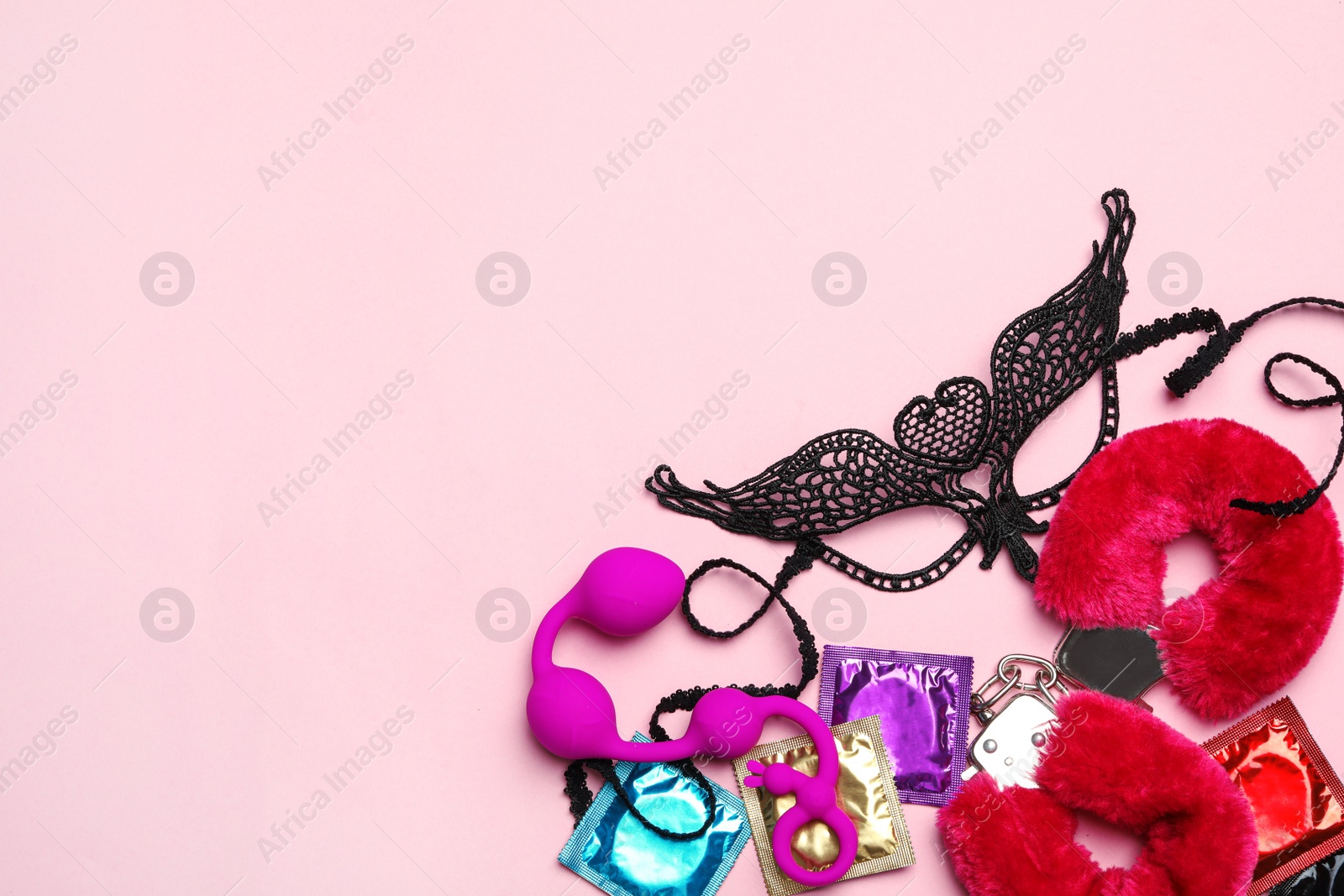 Photo of Different sex toys on pink background, flat lay. Space for text