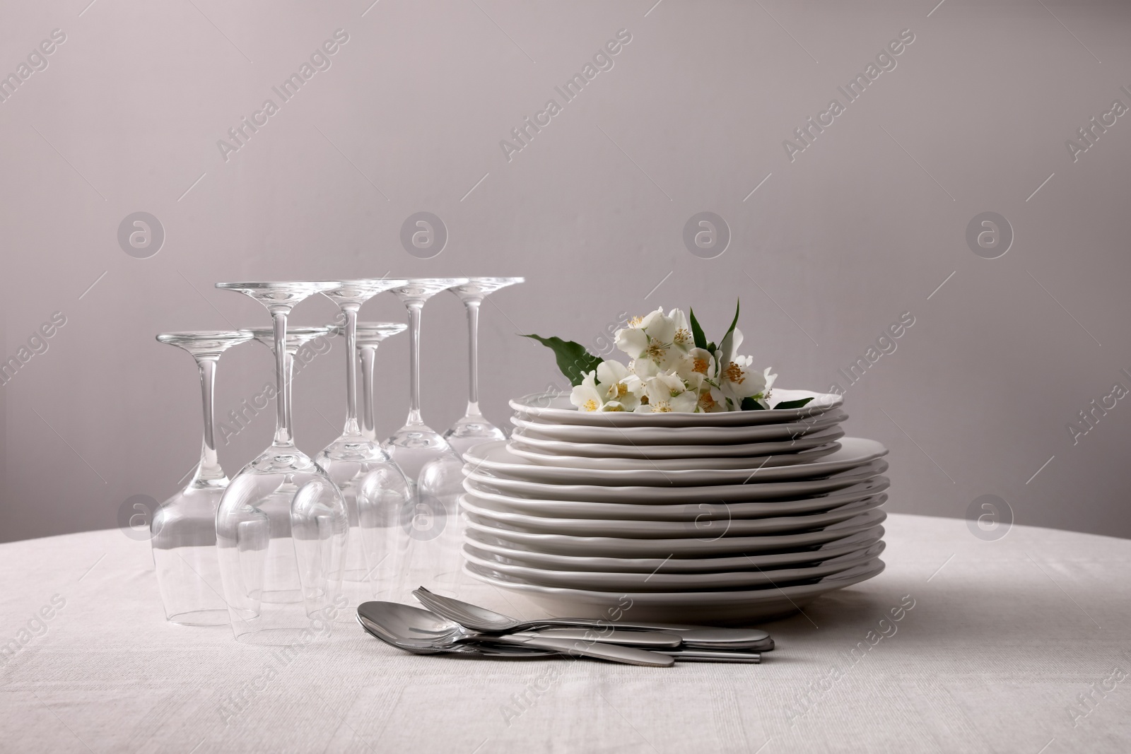 Photo of Set of clean dishware, cutlery and wine glasses on table indoors