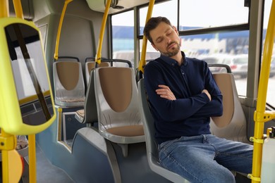 Photo of Tired man sleeping while sitting in public transport