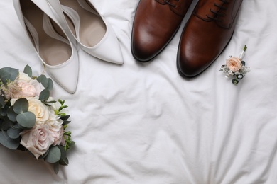 Photo of Flat lay composition with wedding shoes for bride and groom on white fabric. Space for text