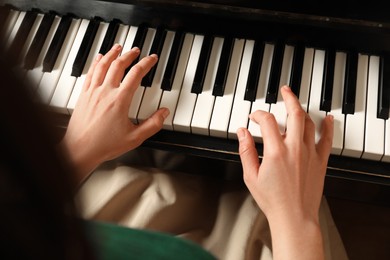 Photo of Young woman playing piano, above view. Music lesson