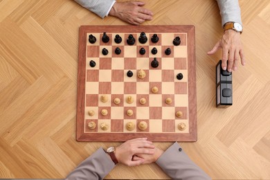 Photo of Player turning on chess clock during tournament at wooden table, top view