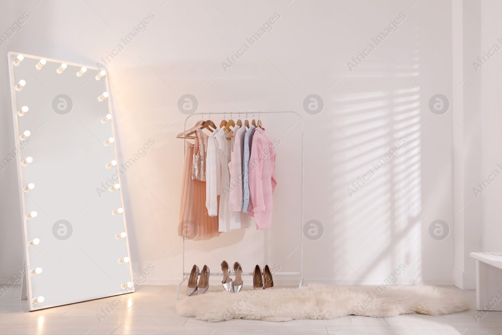 Photo of Rack with stylish women's clothes and mirror indoors. Interior design