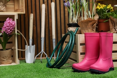 Photo of Composition with different gardening tools on artificial grass at wooden wall