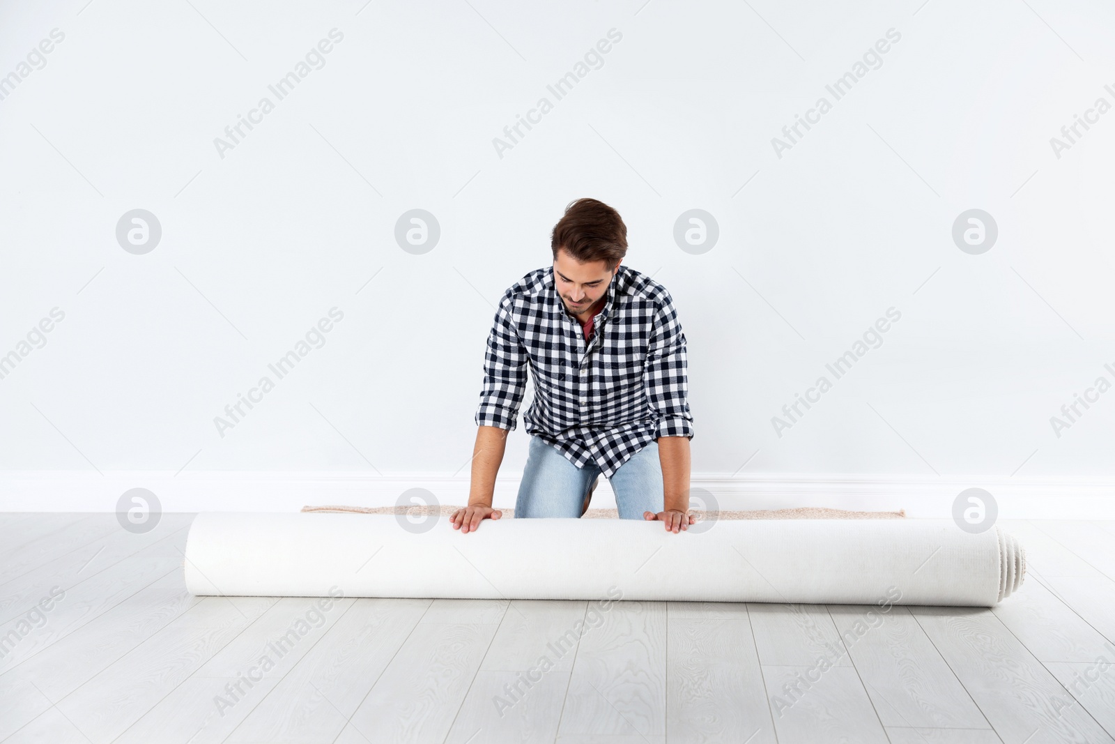 Photo of Man rolling out new carpet flooring indoors