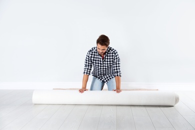 Man rolling out new carpet flooring indoors