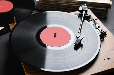 Photo of Modern vinyl record player with disc on black background, closeup