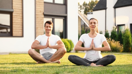 Photo of Sporty couple practicing morning yoga at backyard. Healthy lifestyle