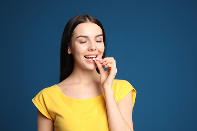 Photo of Young woman taking vitamin pill on blue background