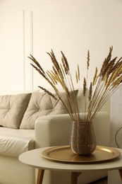 Photo of Fluffy reed plumes on table in living room interior