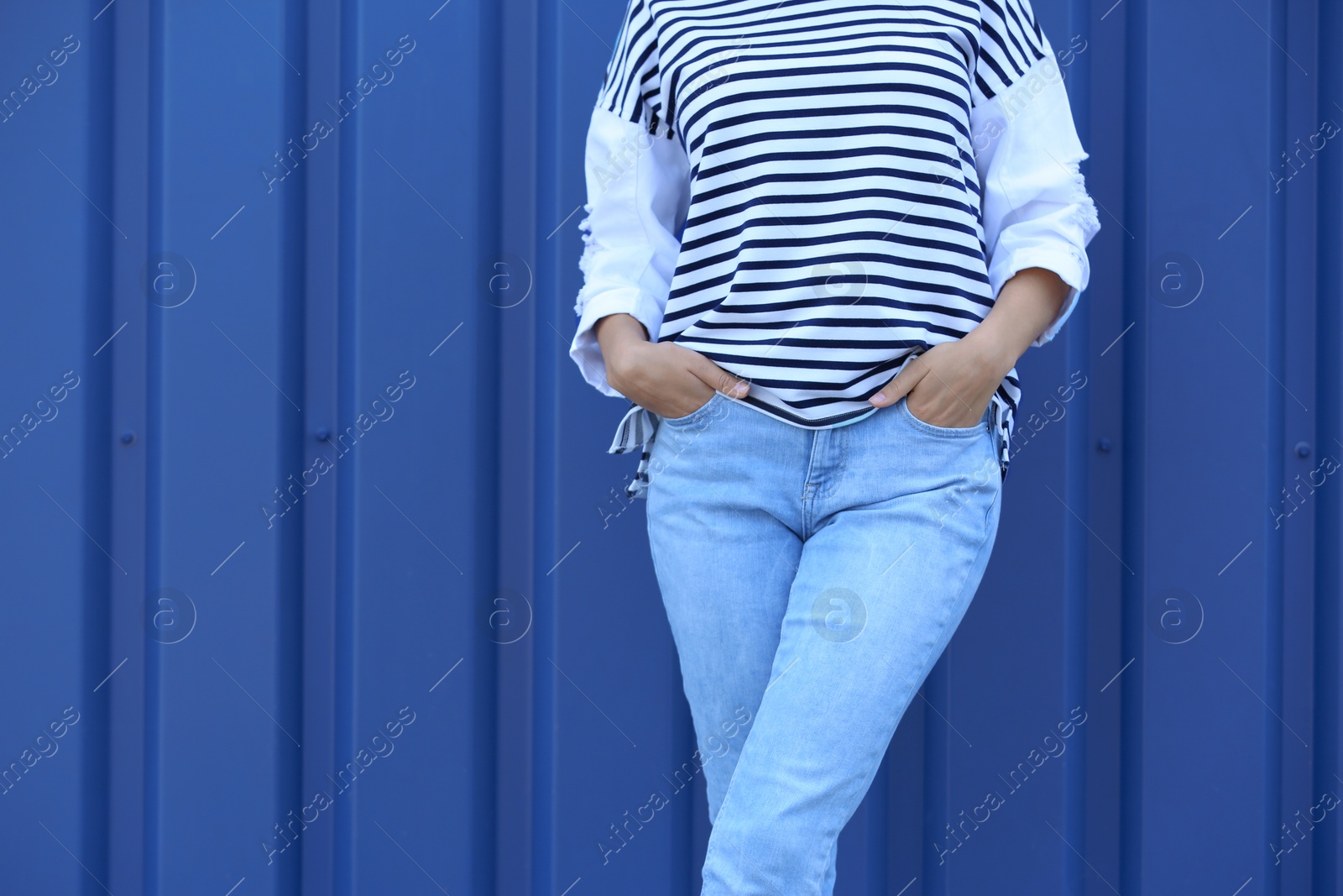 Photo of Young hipster woman in stylish jeans posing near color wall