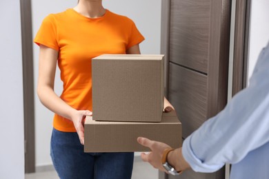 Courier giving parcels to man at house entrance, closeup