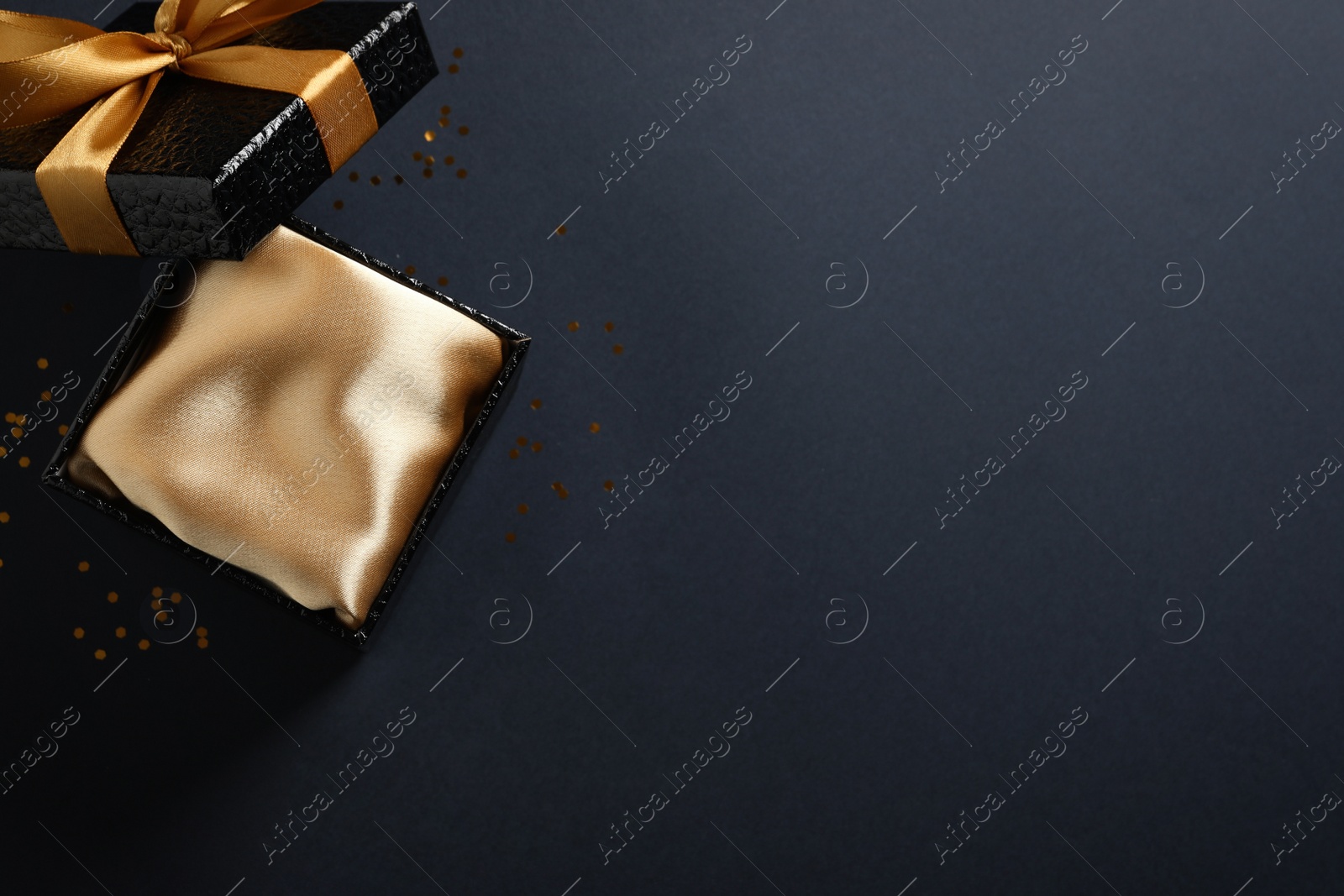 Photo of Open gift box on black background, top view. Space for text