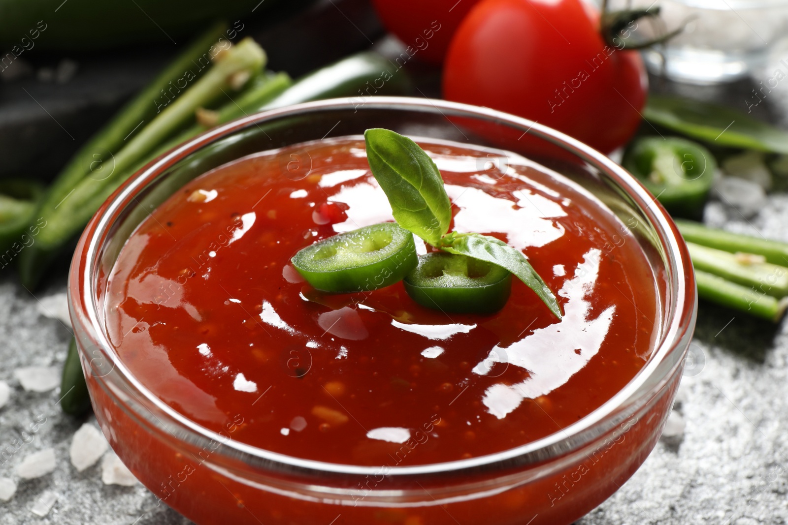 Photo of Spicy chili sauce in glass bowl on table, closeup