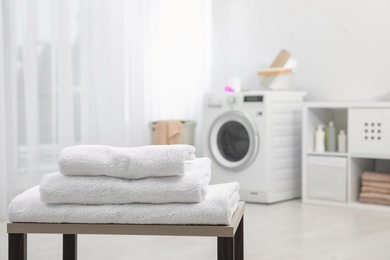 Photo of Stack of clean towels on table in bathroom.  Space for text