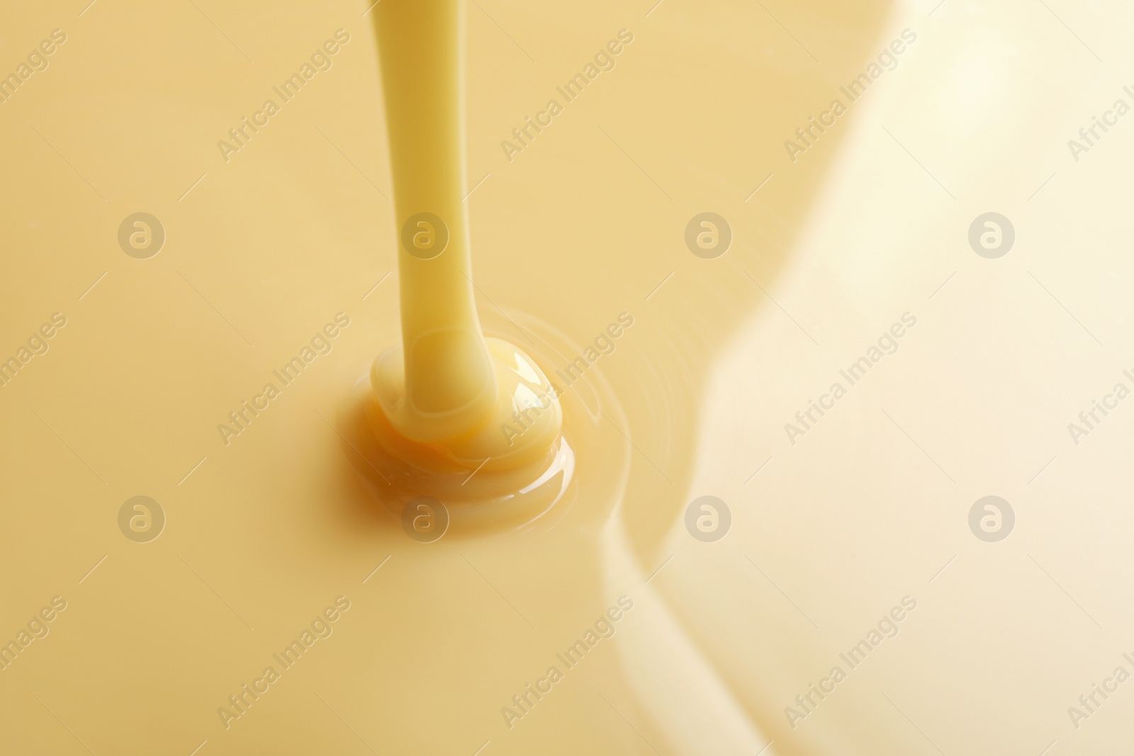 Photo of Tasty pouring condensed milk as background, space for text. Dairy product