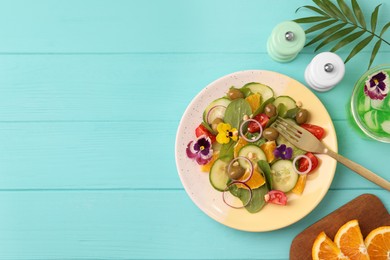 Photo of Delicious salad with orange, spinach, olives and vegetables served on turquoise wooden table, flat lay. Space for text