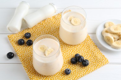 Photo of Tasty yogurt, banana and blueberries on white wooden table