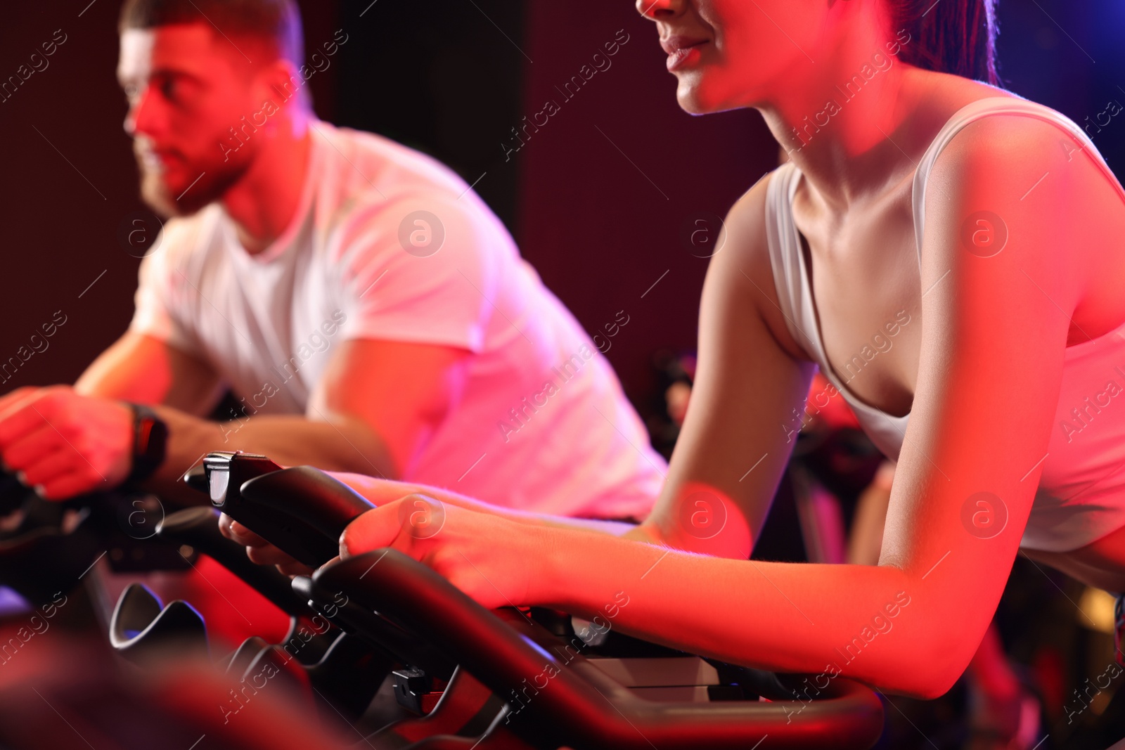 Photo of Woman and man training on exercise bikes in fitness club, closeup