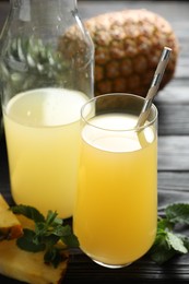 Photo of Delicious fresh pineapple juice on black wooden table