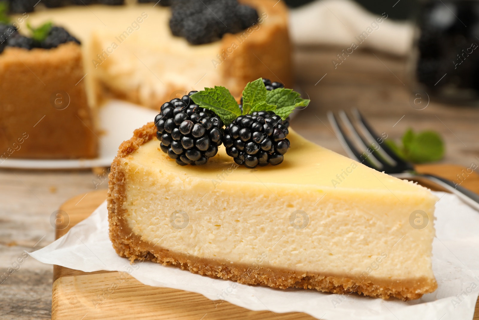 Photo of Piece of delicious cheesecake decorated with blackberries on table