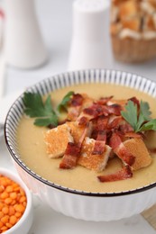 Photo of Delicious lentil soup with bacon and parsley in bowl on table, closeup