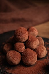 Photo of Tasty chocolate truffles powdered with cacao on slate board