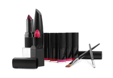 Photo of Different beautiful lipsticks and makeup brushes on white background