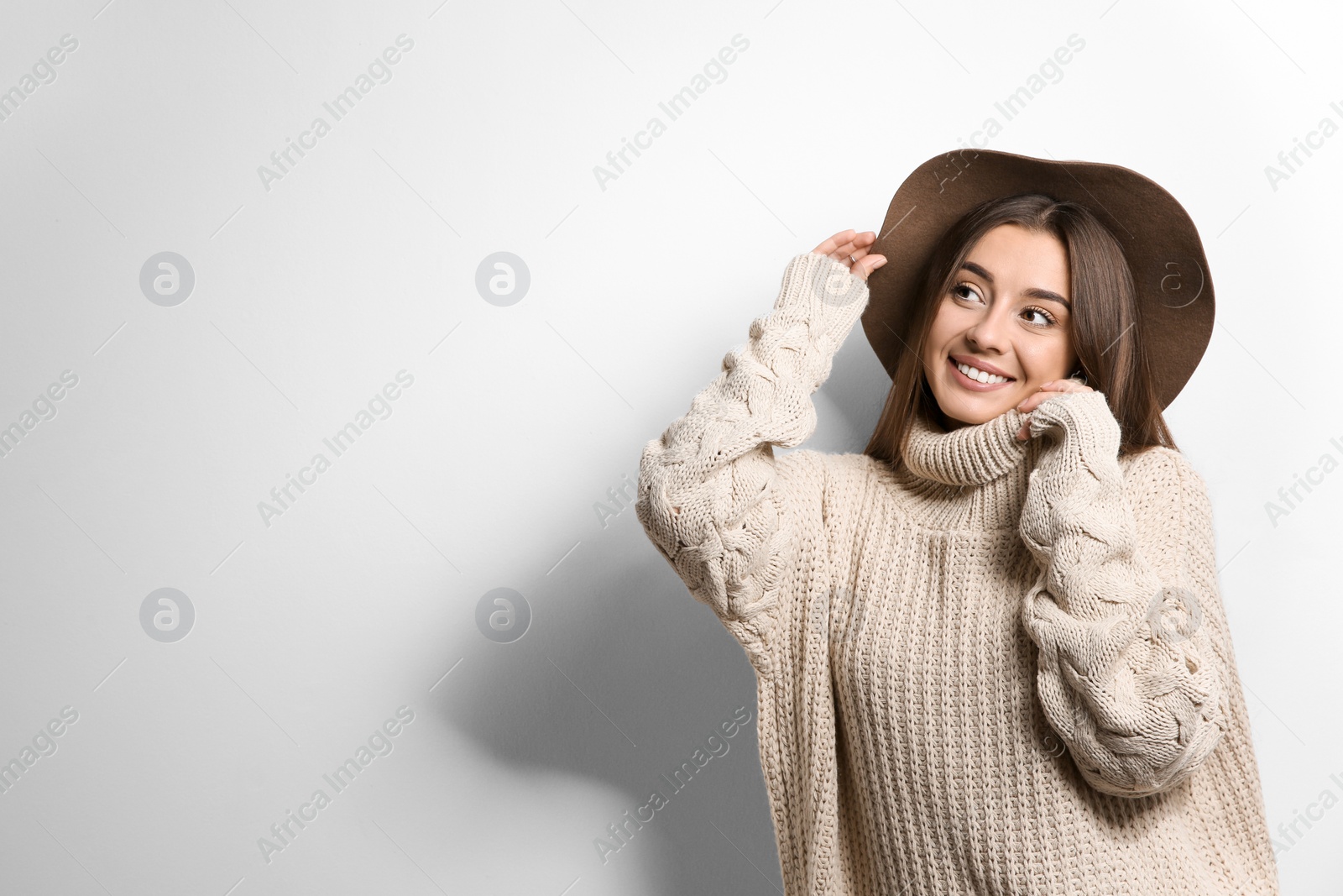 Photo of Beautiful young woman in warm sweater with hat on white background. Space for text