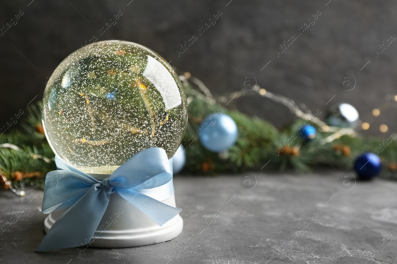 Photo of Beautiful Christmas snow globe on grey table. Space for text