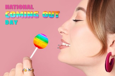 National Coming Out day. Young woman with lip and ear piercings holding rainbow lollipop on pink background, closeup