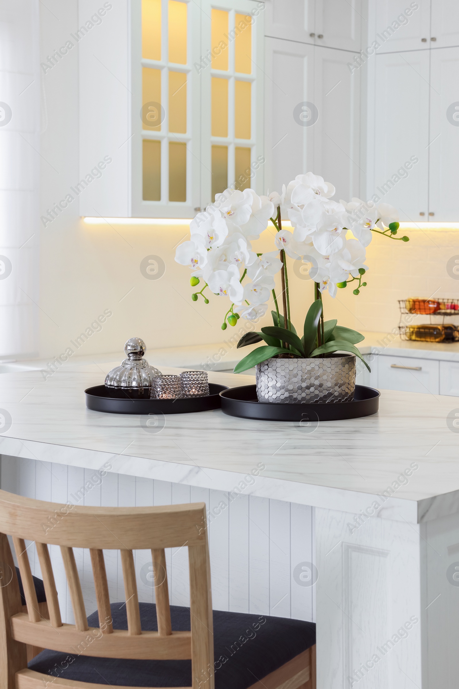 Photo of Beautiful orchid flowers on white marble table in kitchen. Luxury interior