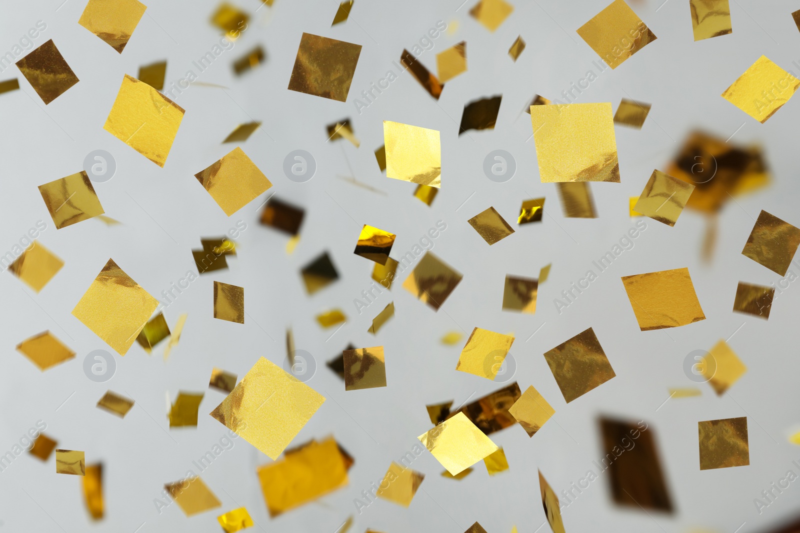 Image of Shiny golden confetti falling down on light grey background