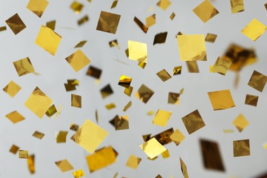 Image of Shiny golden confetti falling down on light grey background