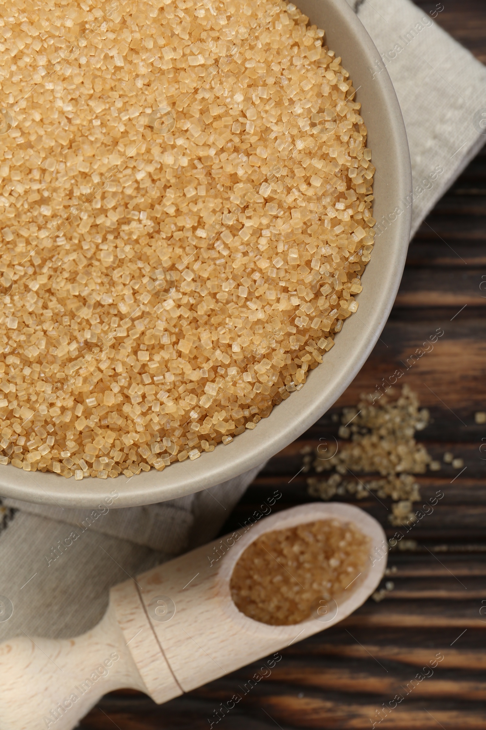 Photo of Brown sugar in bowl and scoop on wooden table, flat lay