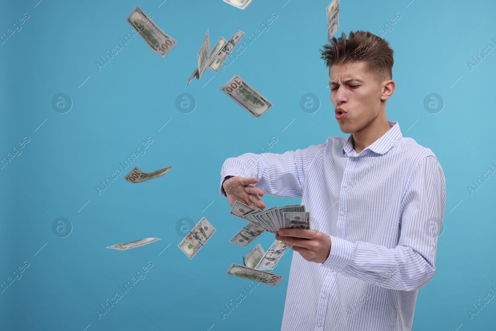 Photo of Handsome man throwing dollar banknotes on light blue background