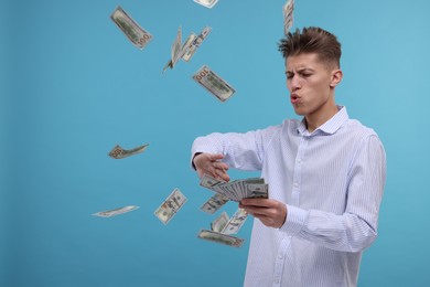 Photo of Handsome man throwing dollar banknotes on light blue background