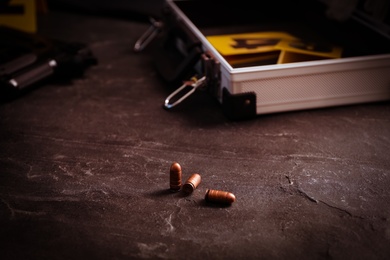 Photo of Bullets on black slate table, closeup. Crime scene