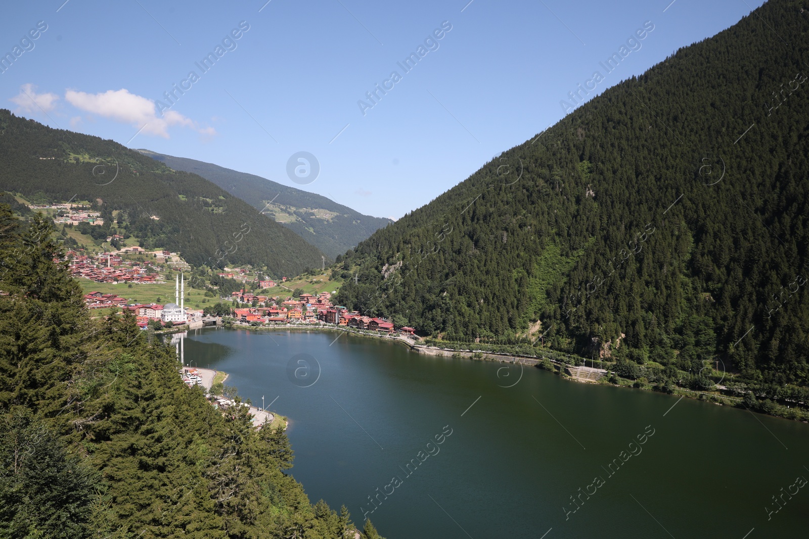 Photo of Buildings under mountains near lake on sunny day