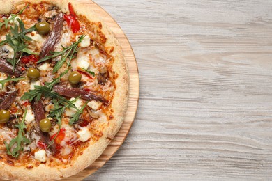Tasty pizza with anchovies, arugula and olives on grey wooden table, top view. Space for text