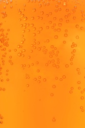 Orange drink with bubbles as background, closeup