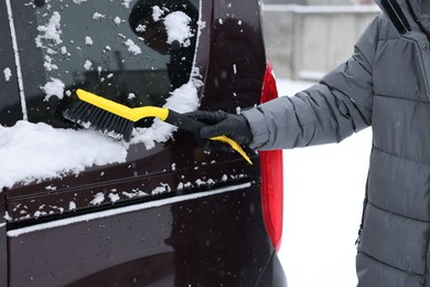 Man cleaning snow from car window outdoors, closeup