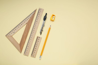 Photo of Different rulers, pencil, and compass on yellow background. Space for text