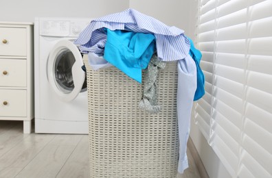 Photo of Plastic laundry basket overfilled with clothes in bathroom
